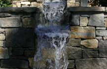Бассейн с каскадным водопадом и стеной из натурального камня